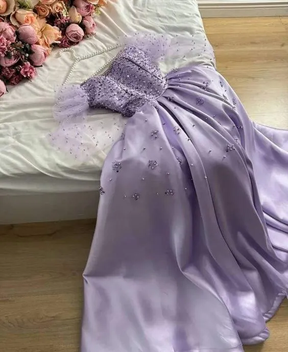 Robe vintage lilas en satin lilas, coupe trapèze, décolleté cœur, ornée de perles et manches longues.