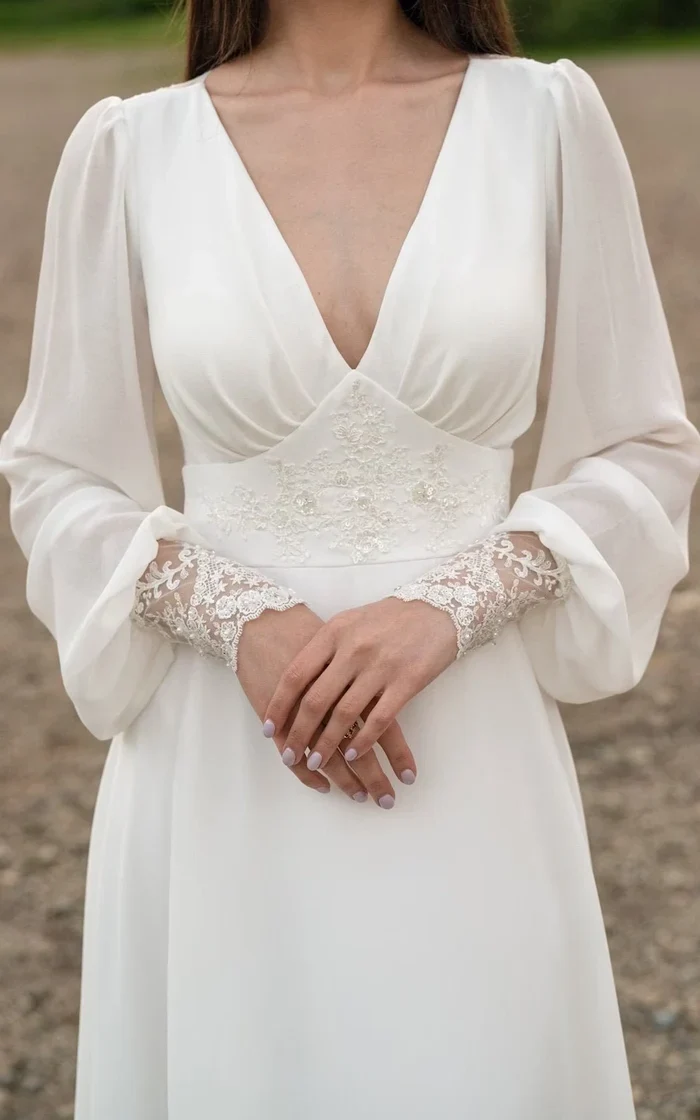 Robe de mariée en mousseline de soie à manches longues et dentelle ivoire avec traîne boutonnée dans le dos