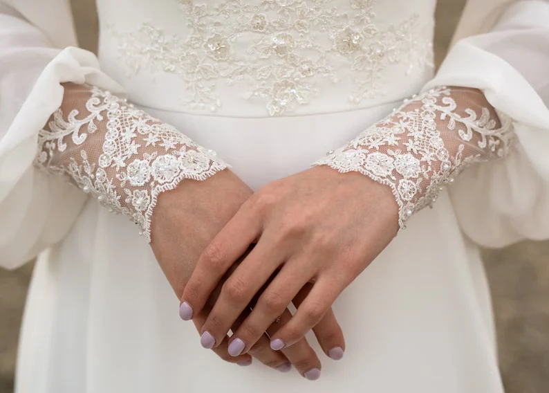 Robe de mariée en mousseline de soie à manches longues et dentelle ivoire avec traîne boutonnée dans le dos