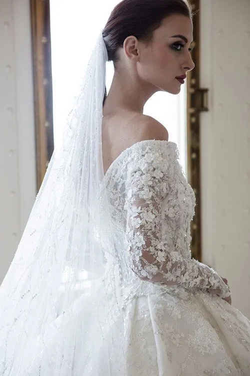 Robe de mariée élégante à épaules dénudées, coupe trapèze, manches longues, dentelle et applications en cristal