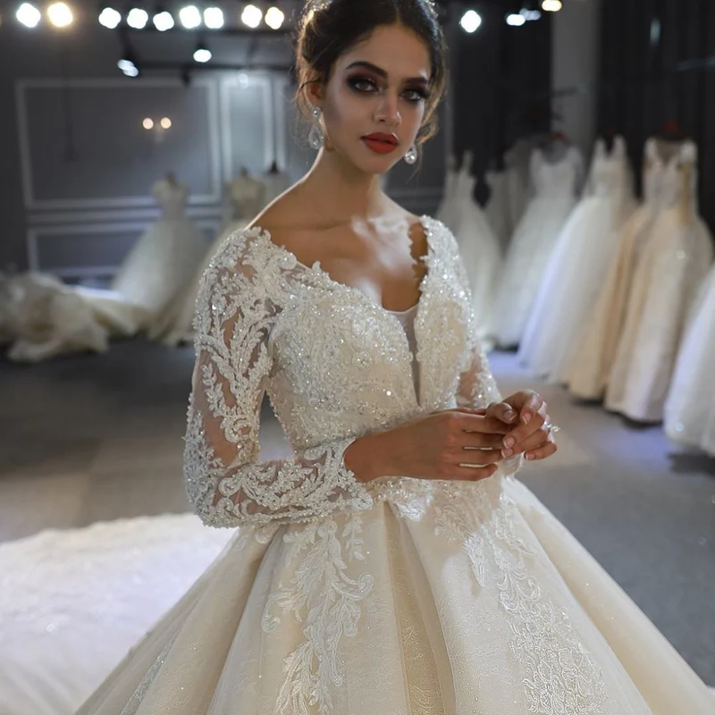 Robe de mariée élégante coupe trapèze, manches longues, appliqués en dentelle et paillettes
