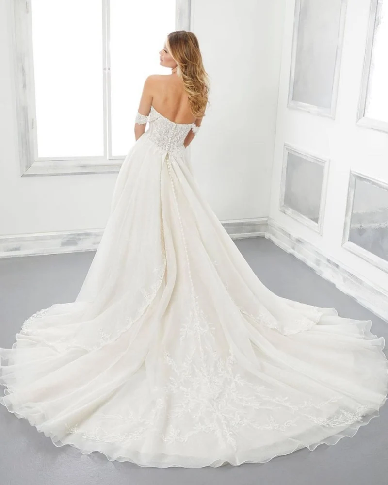 Robe de mariée décolletée en cœur avec traîne, dos nu, coupe trapèze, appliques en dentelle