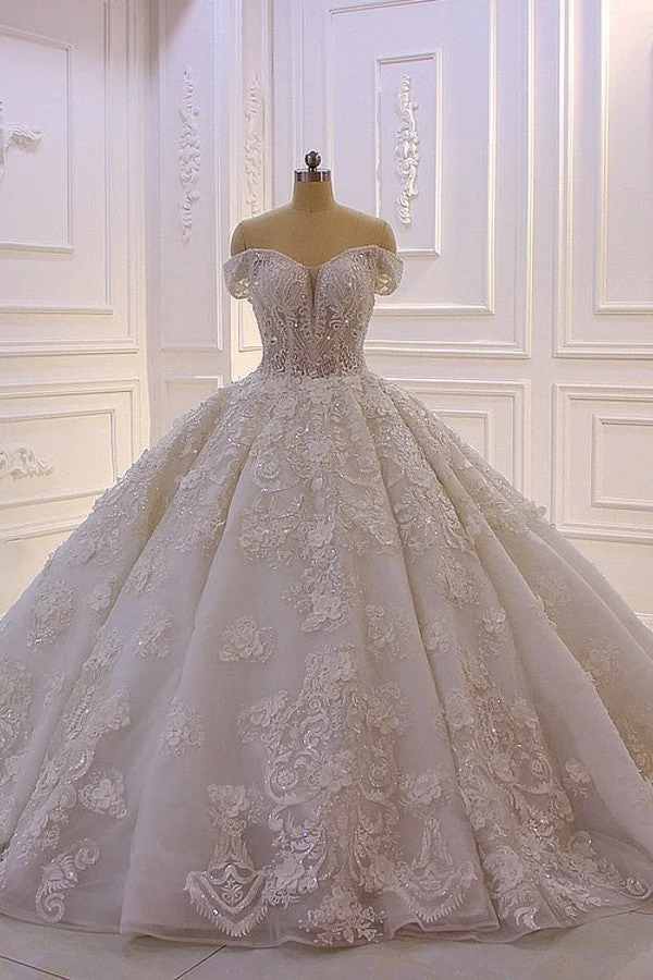 Robe de mariée élégante à épaules dénudées, coupe trapèze, manches longues, appliques et traîne.