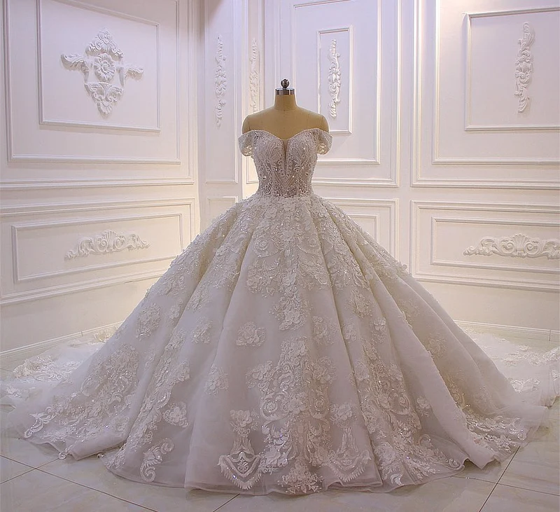 Robe de mariée élégante à épaules dénudées, coupe trapèze, manches longues, appliques et traîne.