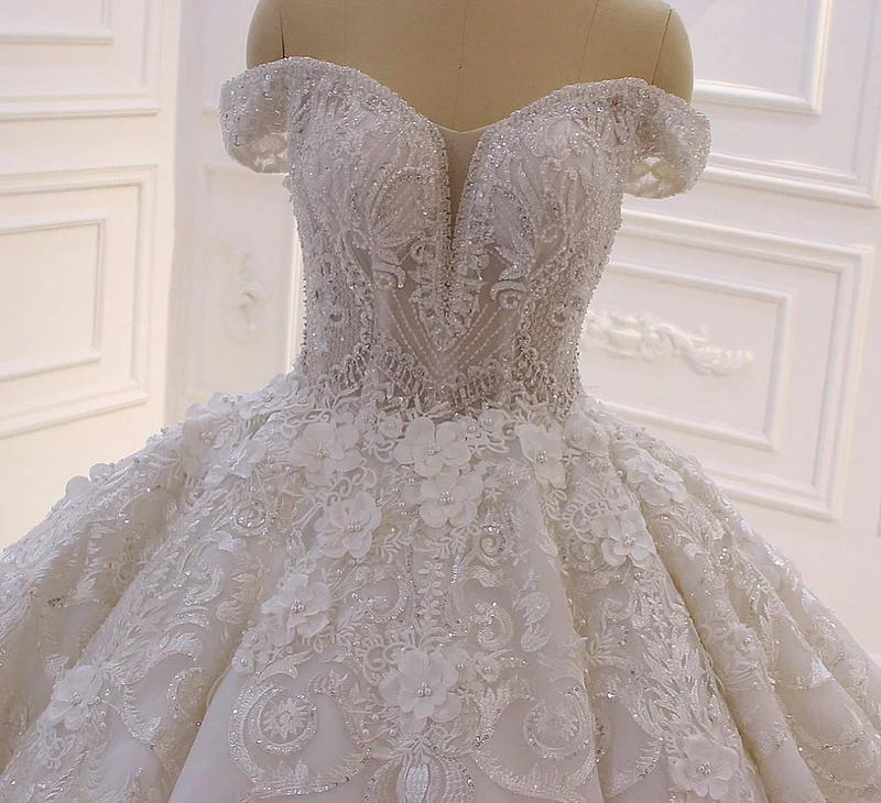 Robe de mariée élégante à épaules dénudées, coupe trapèze, manches longues, appliques et traîne.