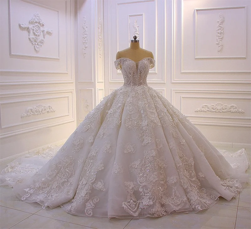 Robe de mariée élégante à épaules dénudées, coupe trapèze, manches longues, appliques et traîne.