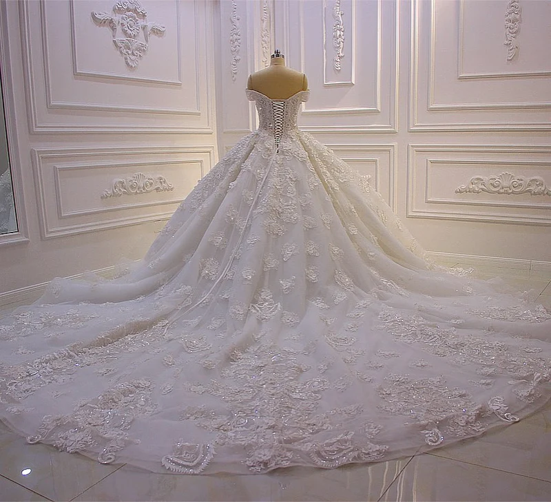 Robe de mariée élégante à épaules dénudées, coupe trapèze, manches longues, appliques et traîne.