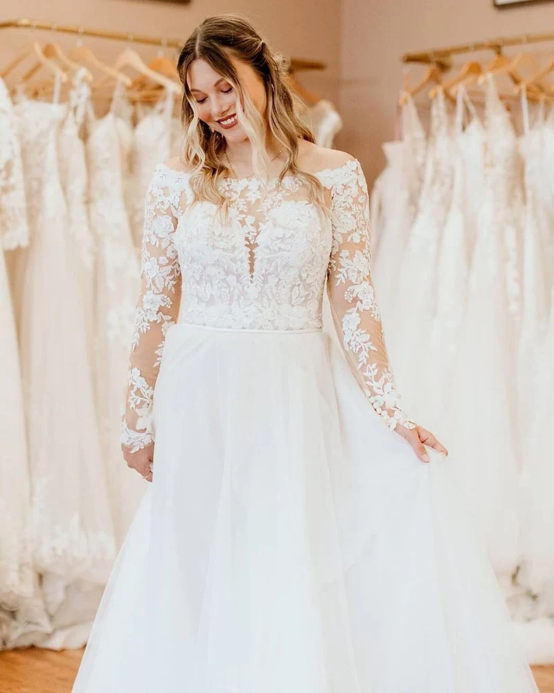 Robe de mariée élégante à épaules dénudées, coupe trapèze, manches longues et dentelle