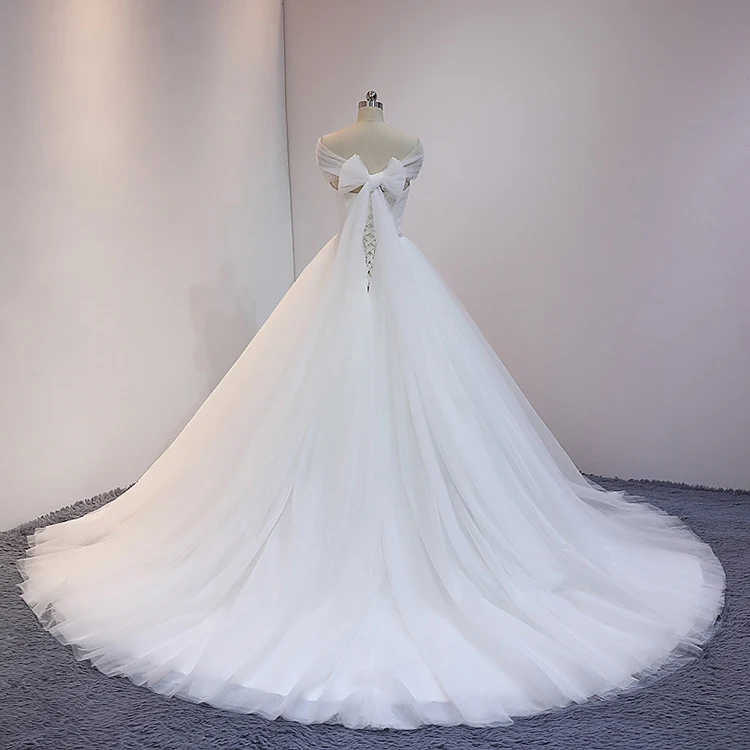 Robe de mariée princesse blanche en tulle avec traîne cathédrale et drapé sur les épaules dénudées