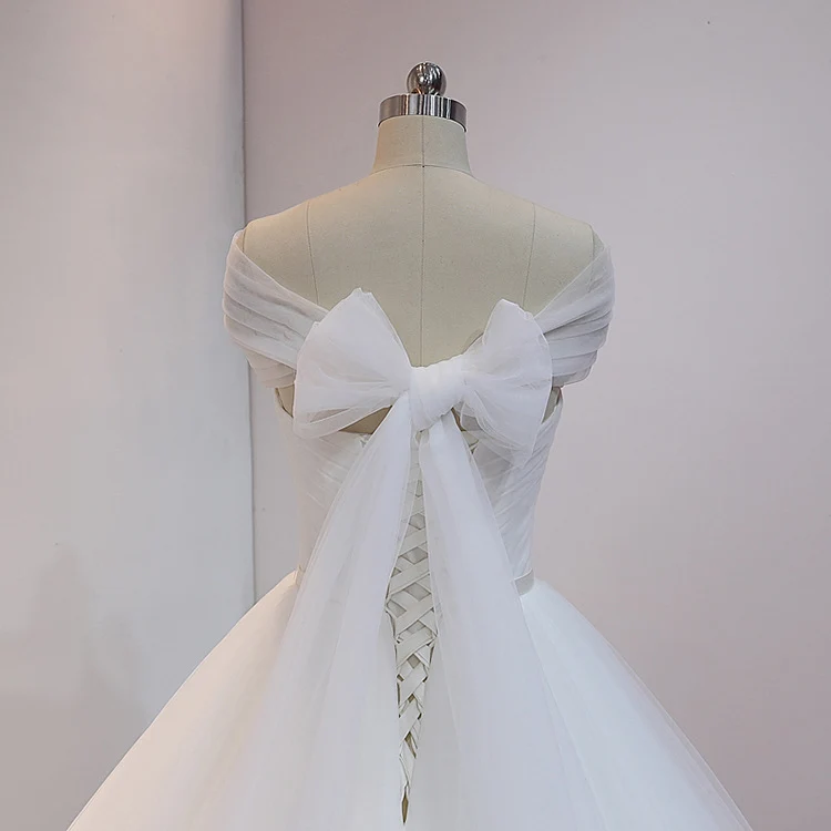 Robe de mariée princesse blanche en tulle avec traîne cathédrale et drapé sur les épaules dénudées