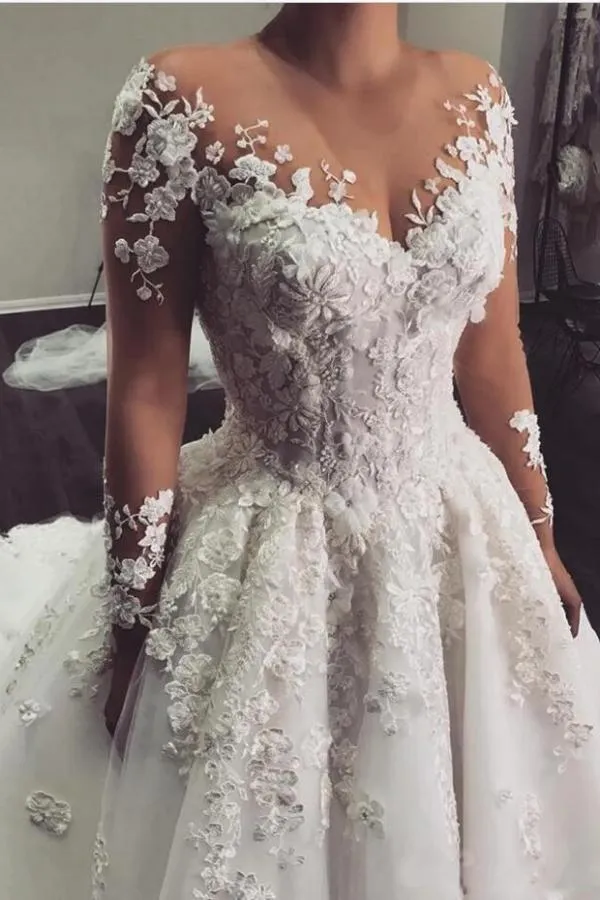 Robe de mariée élégante à manches longues et coupe trapèze, longueur au sol, avec de délicates appliques en dentelle.