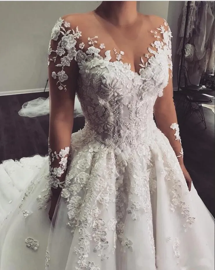 Robe de mariée élégante à manches longues et coupe trapèze, longueur au sol, avec de délicates appliques en dentelle.