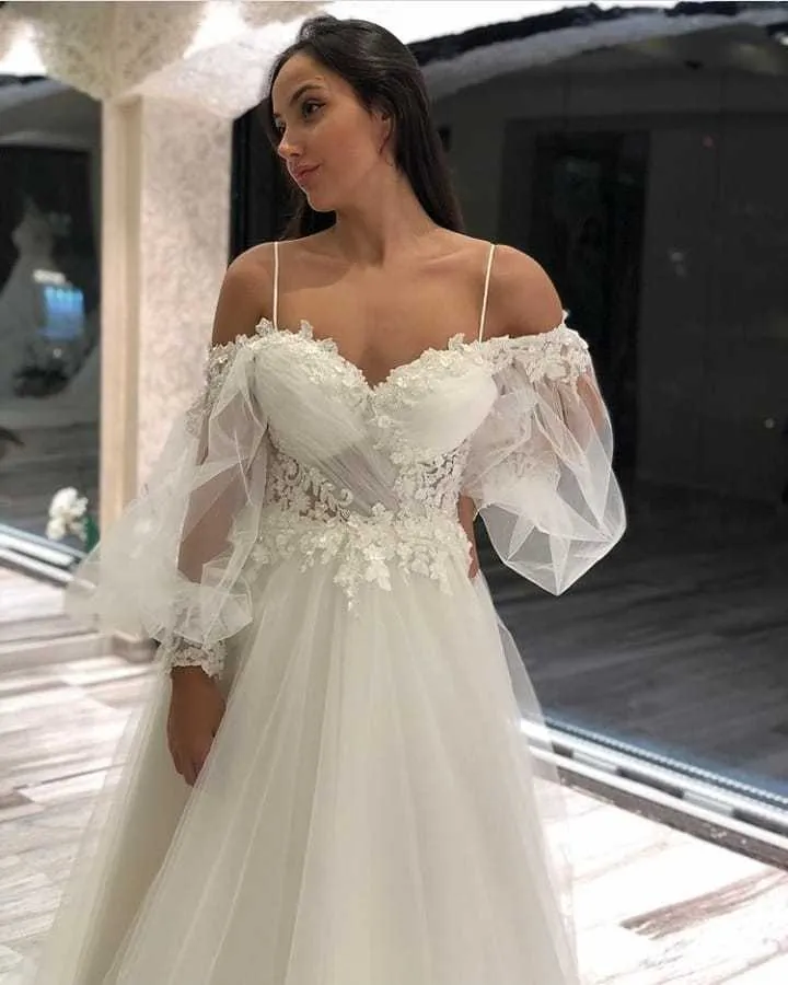 Robe de mariée élégante en tulle et dentelle, coupe trapèze, épaules dénudées, manches longues