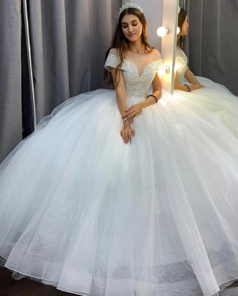 Robe de mariée élégante coupe trapèze, col bateau, traîne en cristal, paillettes et tulle